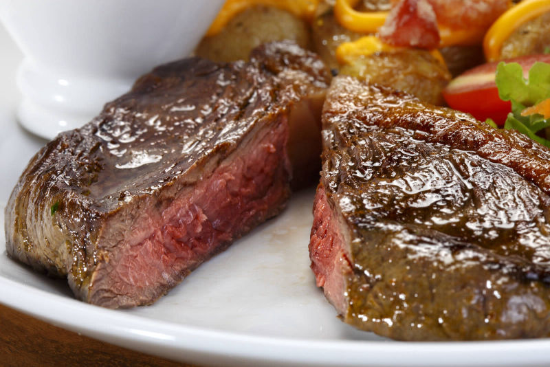 A thick striploin steak cut in two pieces to showcase a medium rare center