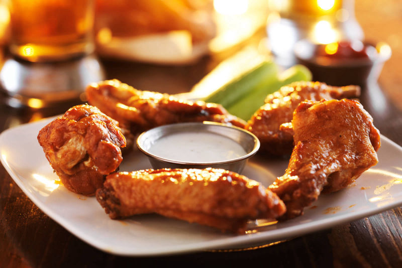 A plate of chicken wings with a Ranch style dip and celery sticks